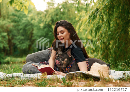 Red book, on the grass. Young pretty woman is with her dog in the park 132216717