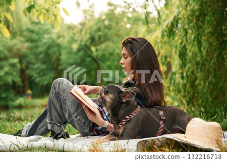 Story reading, red book. Young pretty woman is with her dog in the park 132216718
