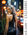 a stunning young woman in a short black dress in the street at night, in front of a streetlights and of automobiles 132216865