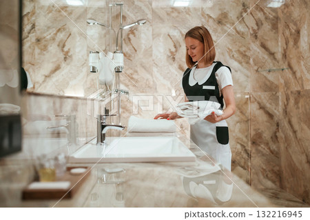In the bathroom. Young chambermaid is in hotel room 132216945