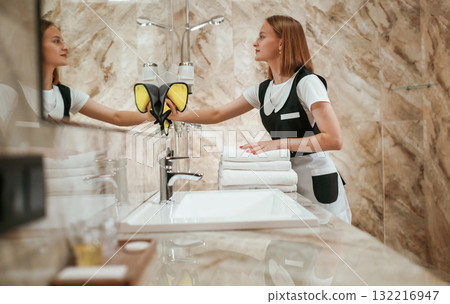 In the bathroom. Young chambermaid is in hotel room 132216947