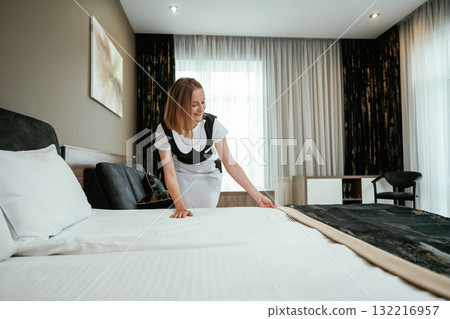 Fresh new cloth for the bed. Young chambermaid is in hotel room Fresh new cloth for the bed. Young chambermaid is in hotel room 132216957