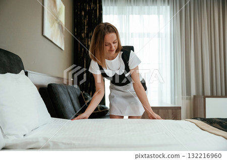 Fresh new cloth for the bed. Young chambermaid is in hotel room Fresh new cloth for the bed. Young chambermaid is in hotel room 132216960