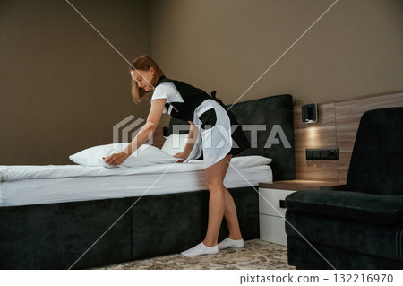 Modern interior, working. Young chambermaid is in hotel room 132216970