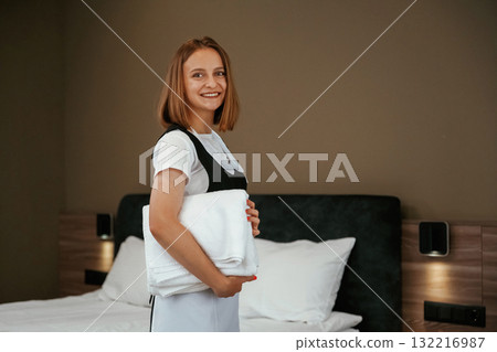 Posing, standing and smiling. Young chambermaid is in hotel room Posing, standing and smiling. Young chambermaid is in hotel room 132216987