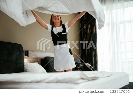 New pillowcase for the bed. Young chambermaid is in hotel room 132217005