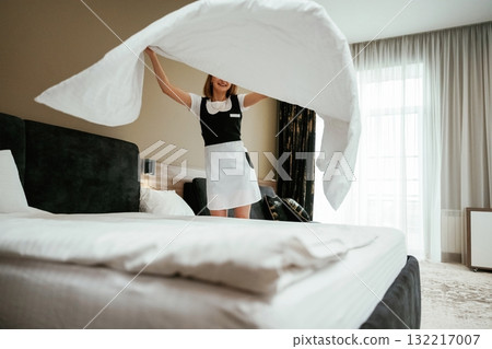 White pillowcase for the bed. Young chambermaid is in hotel room White pillowcase for the bed. Young chambermaid is in hotel room 132217007
