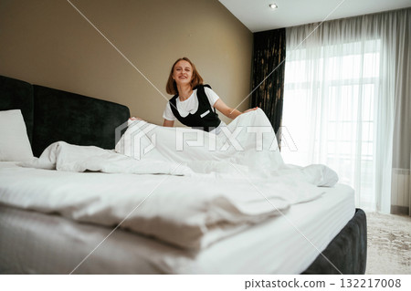 White pillowcase for the bed. Young chambermaid is in hotel room White pillowcase for the bed. Young chambermaid is in hotel room 132217008