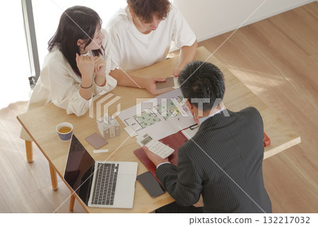 A young couple discussing house building with a salesman A young couple discussing house building with a salesman 132217032