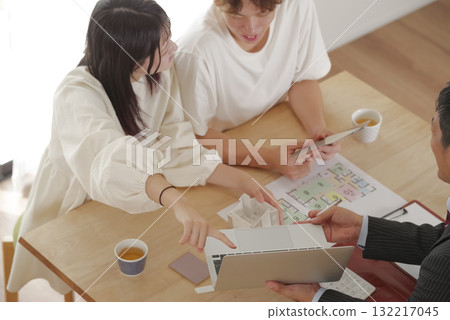 A young couple discussing house building with a salesman A young couple discussing house building with a salesman 132217045