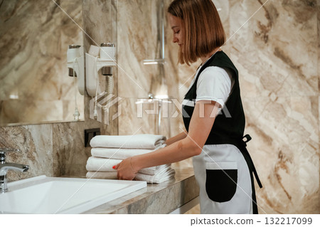 Bathroom interior. Young chambermaid is in hotel room 132217099