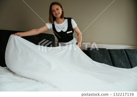 Large new pillow case on the bed. Young chambermaid is in hotel room Large new pillow case on the bed. Young chambermaid is in hotel room 132217139