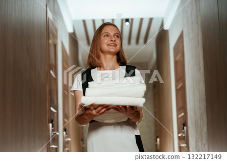 Holding fresh cloth for bed. Chambermaid is standing in the hotel corridor Holding fresh cloth for bed. Chambermaid is standing in the hotel corridor 132217149