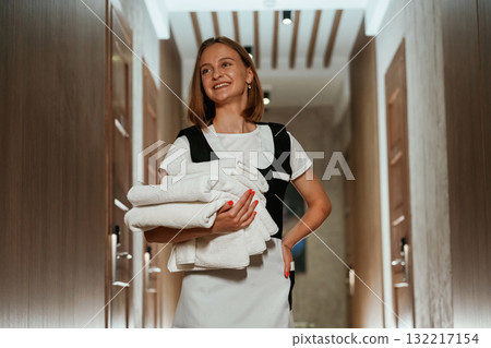 Front view, with fresh cloth. Chambermaid is standing in the hotel corridor Front view, with fresh cloth. Chambermaid is standing in the hotel corridor 132217154