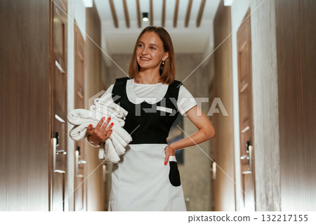 Front view, with fresh cloth. Chambermaid is standing in the hotel corridor Front view, with fresh cloth. Chambermaid is standing in the hotel corridor 132217155