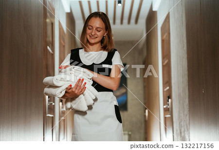 Front view, with fresh cloth. Chambermaid is standing in the hotel corridor Front view, with fresh cloth. Chambermaid is standing in the hotel corridor 132217156