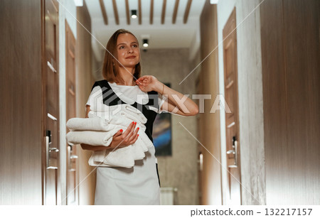 Between the rooms. Chambermaid is standing in the hotel corridor Between the rooms. Chambermaid is standing in the hotel corridor 132217157