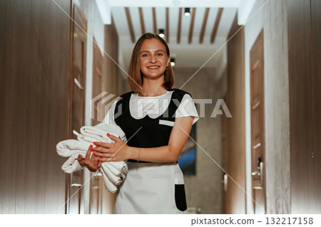 Between the rooms. Chambermaid is standing in the hotel corridor Between the rooms. Chambermaid is standing in the hotel corridor 132217158