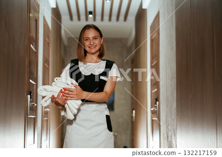 Between the rooms. Chambermaid is standing in the hotel corridor Between the rooms. Chambermaid is standing in the hotel corridor 132217159