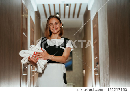 Between the rooms. Chambermaid is standing in the hotel corridor Between the rooms. Chambermaid is standing in the hotel corridor 132217160
