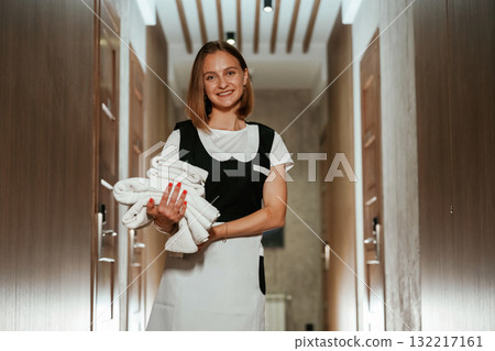 Between the rooms. Chambermaid is standing in the hotel corridor Between the rooms. Chambermaid is standing in the hotel corridor 132217161