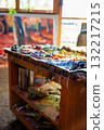Artist creative workspace with oil paint palette, colorful brushstrokes, paint tubes, glass jar, chair and canvas in the background. Real studio atmosphere full of artistic energy. 132217215