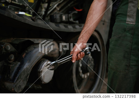 Holding wrench. Mechanic's hand fixing machinery in workshop 132217398