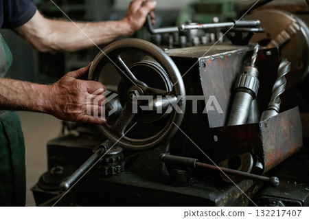 Close-up of worker's hands operating industrial machinery in workshop 132217407