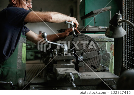 Focused view. Close-up of worker's hands operating industrial machinery in workshop Focused view. Close-up of worker's hands operating industrial machinery in workshop 132217415