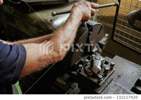 Busy man. Close-up of worker's hands operating industrial machinery in workshop Busy man. Close-up of worker's hands operating industrial machinery in workshop 132217420