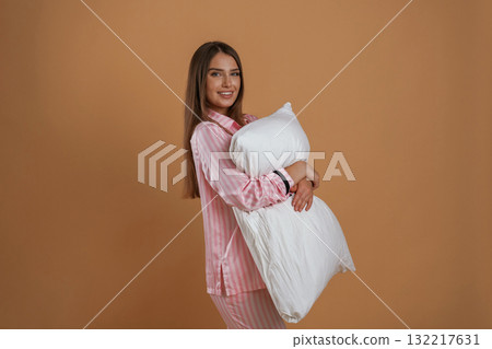 Embracing the pillow. Young pretty woman is against background in the studio 132217631