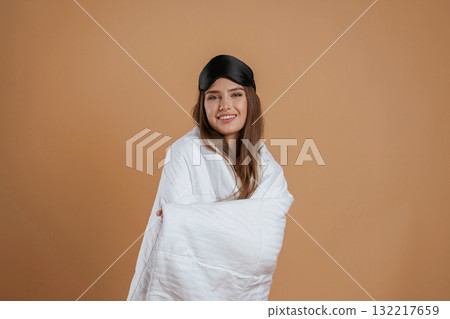 Wrapped in a blanket. Young pretty woman is against background in the studio Wrapped in a blanket. Young pretty woman is against background in the studio 132217659