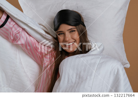 Just woke up, in pajama and on the pillow. Young pretty woman is against background in the studio Just woke up, in pajama and on the pillow. Young pretty woman is against background in the studio 132217664