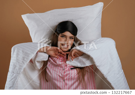 Just woke up, in pajama and on the pillow. Young pretty woman is against background in the studio Just woke up, in pajama and on the pillow. Young pretty woman is against background in the studio 132217667