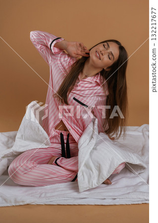 Doing morning stretches, on the ground. Young pretty woman is against background in the studio Doing morning stretches, on the ground. Young pretty woman is against background in the studio 132217677