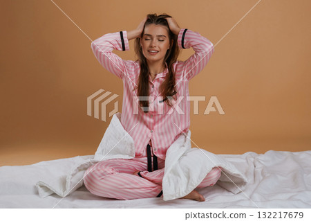 Doing morning stretches, on the ground. Young pretty woman is against background in the studio Doing morning stretches, on the ground. Young pretty woman is against background in the studio 132217679