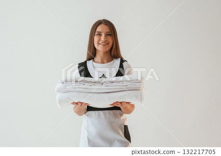 Chambermaid is standing. Young pretty woman is against background in the studio Chambermaid is standing. Young pretty woman is against background in the studio 132217705