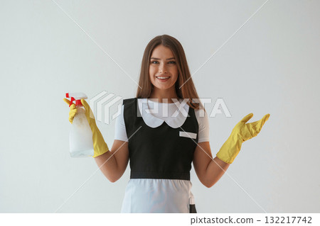 Chambermaid is with cleaning product and tool. Young pretty woman is against background in the studio Chambermaid is with cleaning product and tool. Young pretty woman is against background in the studio 132217742