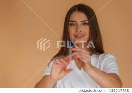 Vaccination concept, nurse is with syringe. Young pretty woman is against background in the studio 132217758