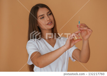 Vaccination concept, nurse is with syringe. Young pretty woman is against background in the studio 132217760
