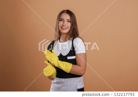 Done, work is finished, chambermaid is in yellow gloves. Young pretty woman is against background in the studio Done, work is finished, chambermaid is in yellow gloves. Young pretty woman is against background in the studio 132217791