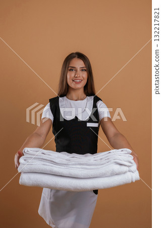 Brand new towels, chambermaid is standing. Young pretty woman is against background in the studio Brand new towels, chambermaid is standing. Young pretty woman is against background in the studio 132217821