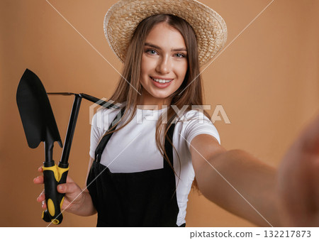 Labor conception. Gardener is with tools. Young pretty woman is against background in the studio Labor conception. Gardener is with tools. Young pretty woman is against background in the studio 132217873