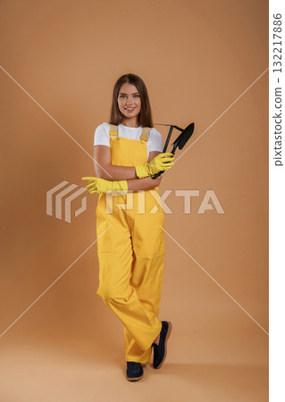 Little shovel for gardening. Young pretty woman is against background in the studio 132217886