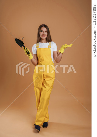 Little shovel for gardening. Young pretty woman is against background in the studio 132217888