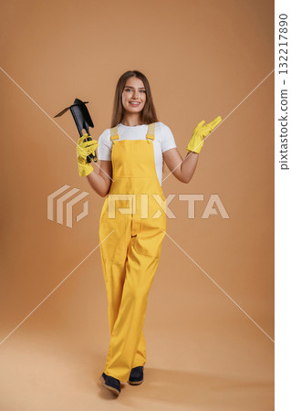 Little shovel for gardening. Young pretty woman is against background in the studio Little shovel for gardening. Young pretty woman is against background in the studio 132217890