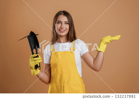 Little shovel for gardening. Young pretty woman is against background in the studio Little shovel for gardening. Young pretty woman is against background in the studio 132217891