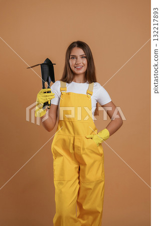 Little shovel for gardening. Young pretty woman is against background in the studio Little shovel for gardening. Young pretty woman is against background in the studio 132217893