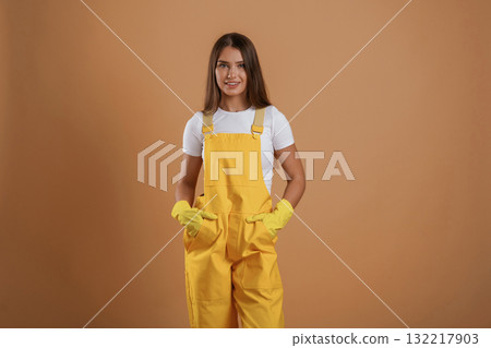 Hands in pockets, gardener is standing. Young pretty woman is against background in the studio 132217903