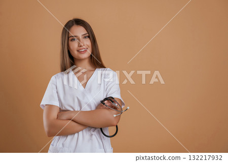 Pretty nurse is in white clothes. Young woman is against background in the studio Pretty nurse is in white clothes. Young woman is against background in the studio 132217932